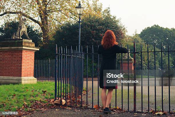 Woman Leaning On Gate In Park Stock Photo - Download Image Now - Adult, Adults Only, Autumn