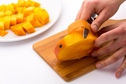 Dividing the mango into three equally-sized slices, we are left with the middle slice containing the stone. The fruit pulp can easily be separated from the peel with a sharp kitchen knife and cut into cubes.