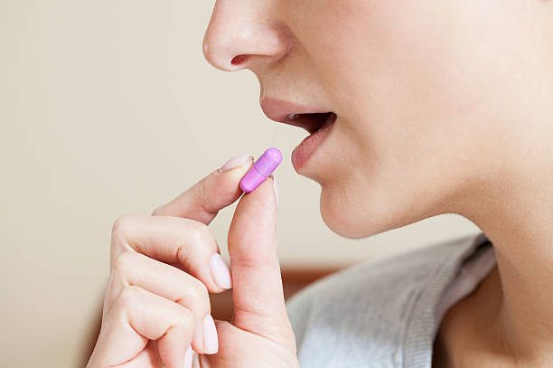 istock Close-up of woman taking pill 526024357