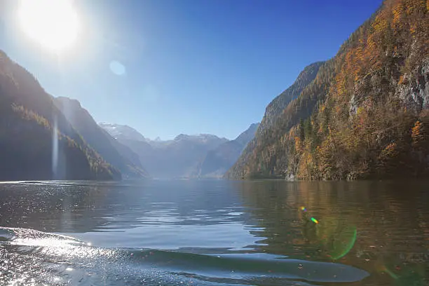 The KÃ¶igssee in the alps with bright sunlight in front. Picture made at autumn on a suny day. the water is green .