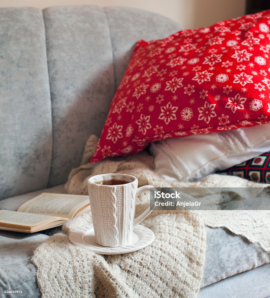 Still life interior details, cup of tea and book Still life interior details, cup of tea and book on the sofa with pillows Christmas Stock Photo