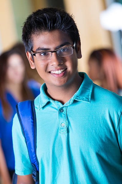istock Happy Indian student using smart phone in high school hallway 526040223