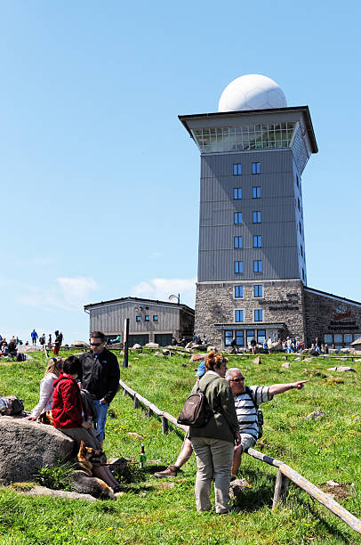 Peak of Brocken Mountain at Harz National Park (Germany) Brocken, Germany - May 26, 2012: Peak of Brocken Mountain at Harz National Park (Saxony-anhalt, Germany) with its typical white communication tower and the Hotel at Brocken with two restaurants. In front a group of hiking people walking around on peak. sendemast stock pictures, royalty-free photos & images