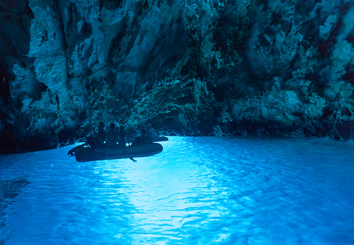 Bisevo, Croatia - August 20, 2012: Tourists in inflatable boats inside the Blue cave, famous tourist attraction.
