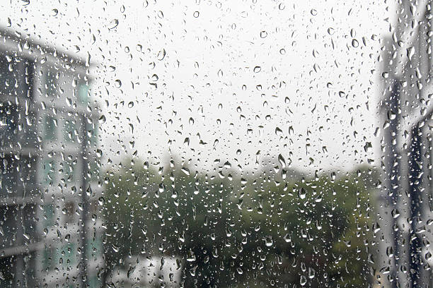 istock Drops of rain on a window pane, buildings in background. 526059333