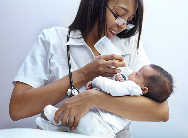 Making a caring contribution to society Shot of a healthcare worker giving formula to an infant who has a cleft palate cleft lip stock pictures, royalty-free photos & images