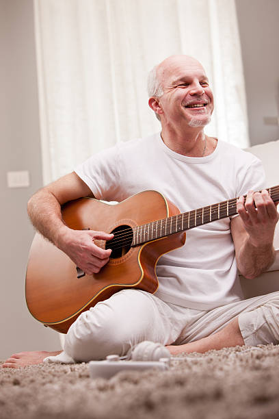 istock mature man playing guitar at home 526060021