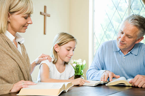 Family Reading Bibles at Table Family Reading Bibles at Table bible study group of people small group of people stock pictures, royalty-free photos & images