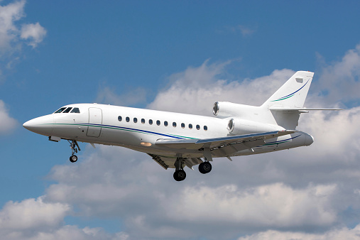 Dassault Falcon business jet flying against a blue sky with scattered clouds