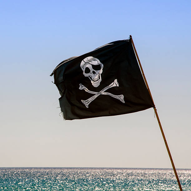 istock pirate flag waving with blue sea background 526069807