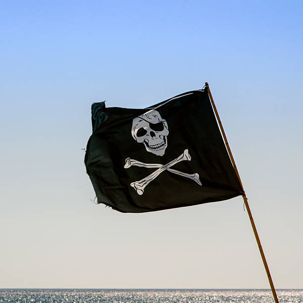 istock pirate flag waving with blue sea background 526069809