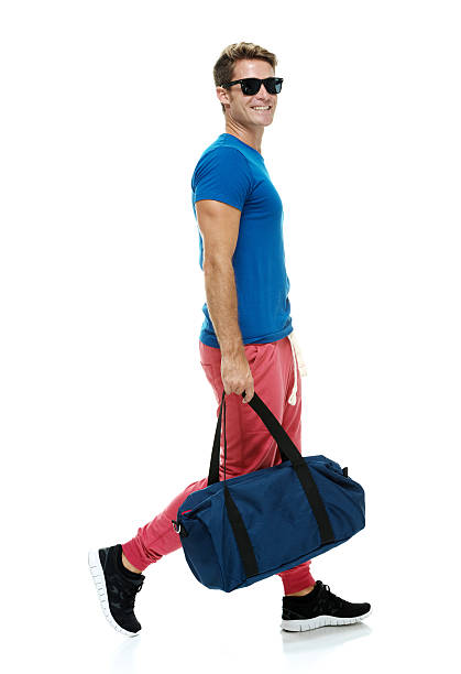 istock Happy smart casual man holding duffle bag & walking 526086367