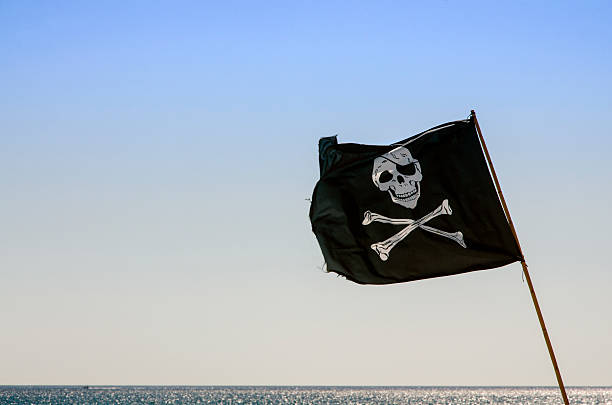 istock pirate flag waving with blue sea background 526087071