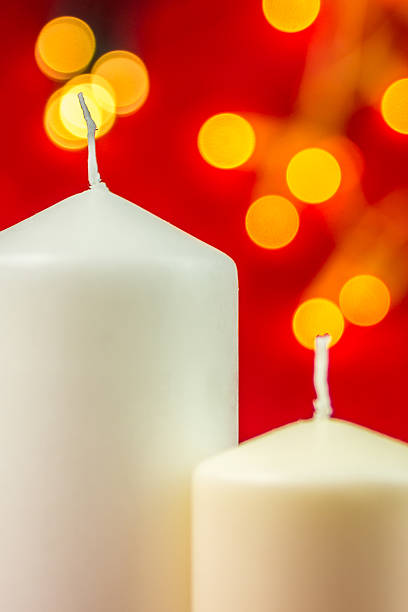 istock Two white christmas wax candles on red background 526089867