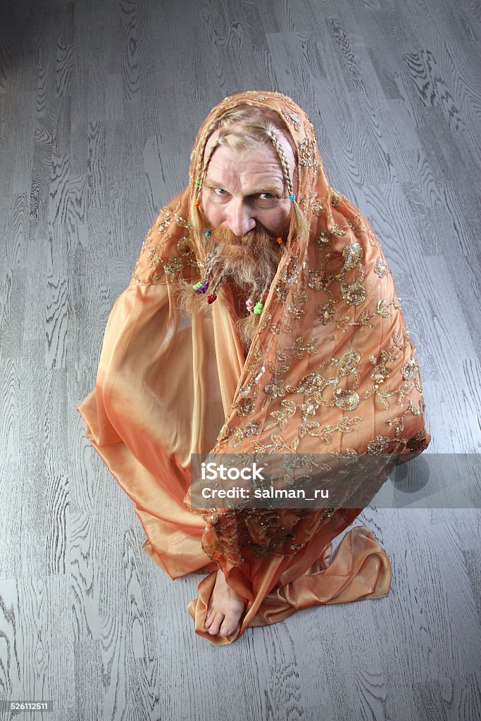 portrait of a man with beige scarf portrait of a man with a long beard, mustache and hair braided in pigtails sitting in lotus wrapped in a beige scarf studio on light backgroundportrait of a man with a long beard, mustache and hair braided in pigtails sitting in lotus wrapped in a beige scarf studio on light background Adult Stock Photo
