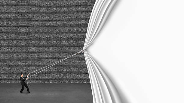 businessman pulling down white curtain covering old dark brick wall on gray concrete floor