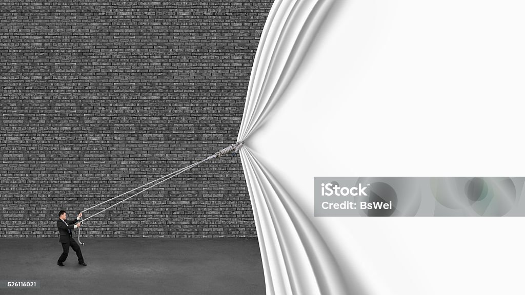 businessman pulling down white curtain covering old dark brick w businessman pulling down white curtain covering old dark brick wall on gray concrete floor Discovery Stock Photo