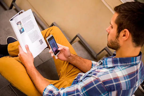 Man scanning qr code from magazine with smartphone