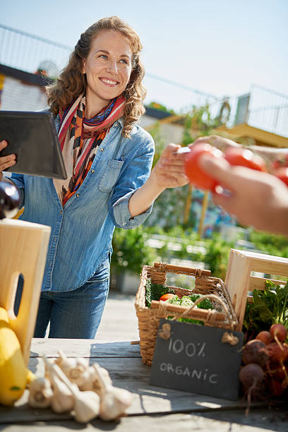 istock Friendly woman tending an organic vegetable stall at a farmer 526124884