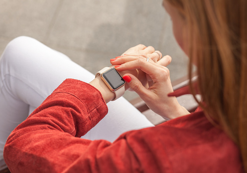 young woman use smartwatch with blank screen outdoor, view of shoulder