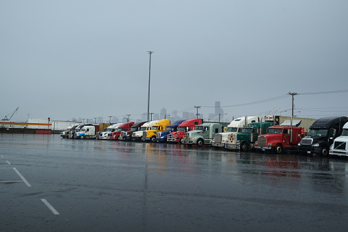 Seattle, Washington, USA - March 6, 2016: A row of semi trucks parked in a lot in the rain