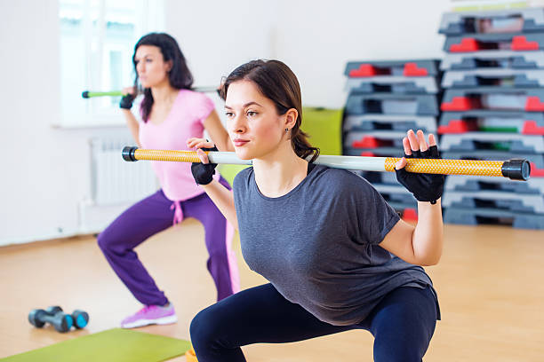 istock Group of people excercising with bars in gym doing squatting 526128634