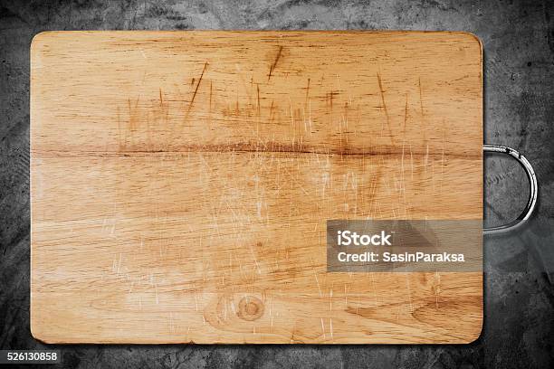 Old Scratched Wooden Cutting Board On Dark Concrete Texture Stock Photo - Download Image Now