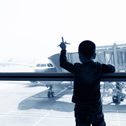 Young asian boy playing a toy plane in airport and waiting for departure.