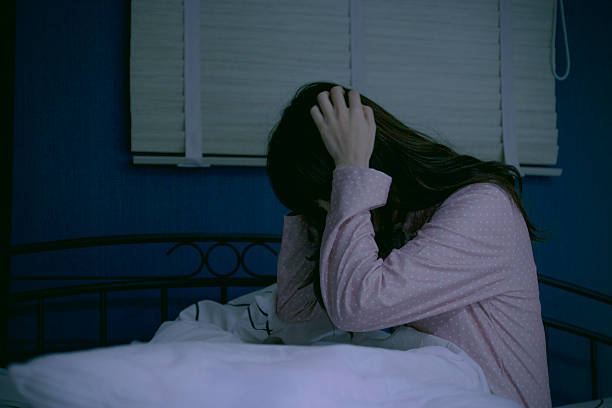 istock Woman holding her head on bed at night 526136660