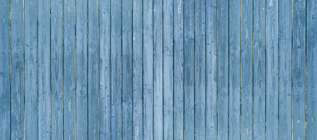 Panorama of a blue, slightly weathered board wall 