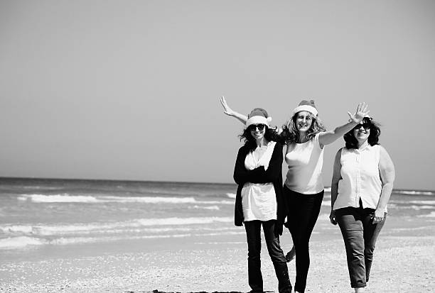 Three beautiful women wearing christmas hat walking on the seaside