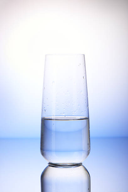 istock Half-filled drinking glass in drops of water 526142288