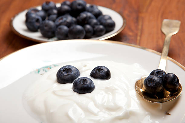 healthy breakfast with natural yoghurt and blueberries on wooden table, in vintage porcelain plate, with golden spoon,