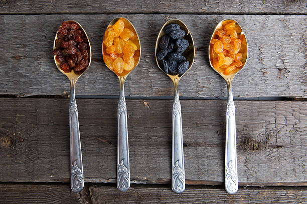 istock Raisins in metal spoons on wooden table 526145964