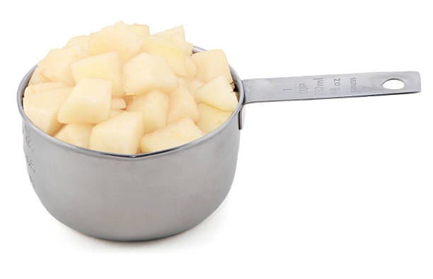 Diced pear flesh in a cup measure Diced pear flesh in an American cup measure, isolated on a white background conference pear stock pictures, royalty-free photos & images