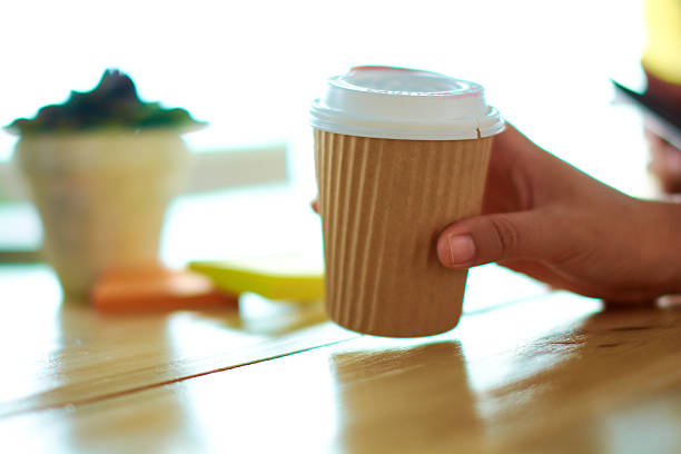Close up of a hand holding a cappuccino during a morning team presentation