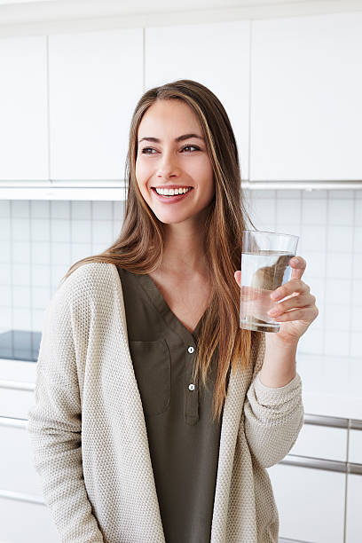 jolie femme dans la cuisine avec de l " eau - water women glass healthy eating photos et images de collection