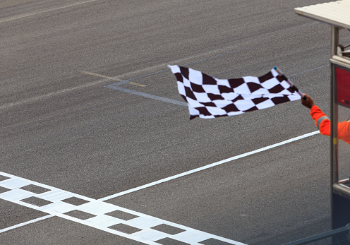 A checkered flag waving at an car race. Waving check flag in air at race finish, motion blur on flag.