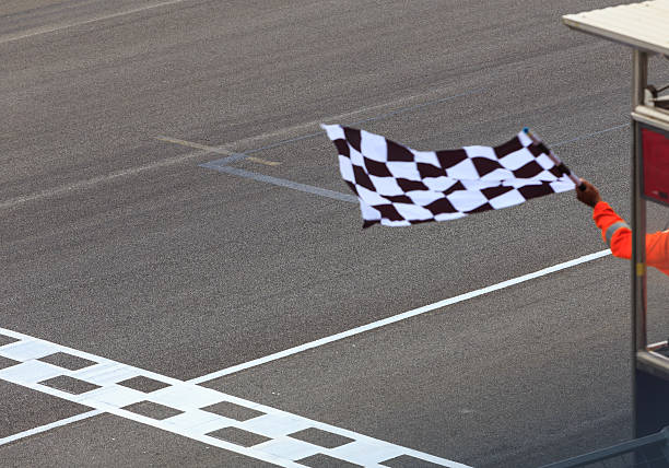 Checkered flag waving A checkered flag waving at an car race. Waving check flag in air at race finish, motion blur on flag. auto racing photos stock pictures, royalty-free photos & images