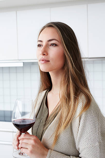 istock Thoughtful young woman with wine in kitchen 526153126