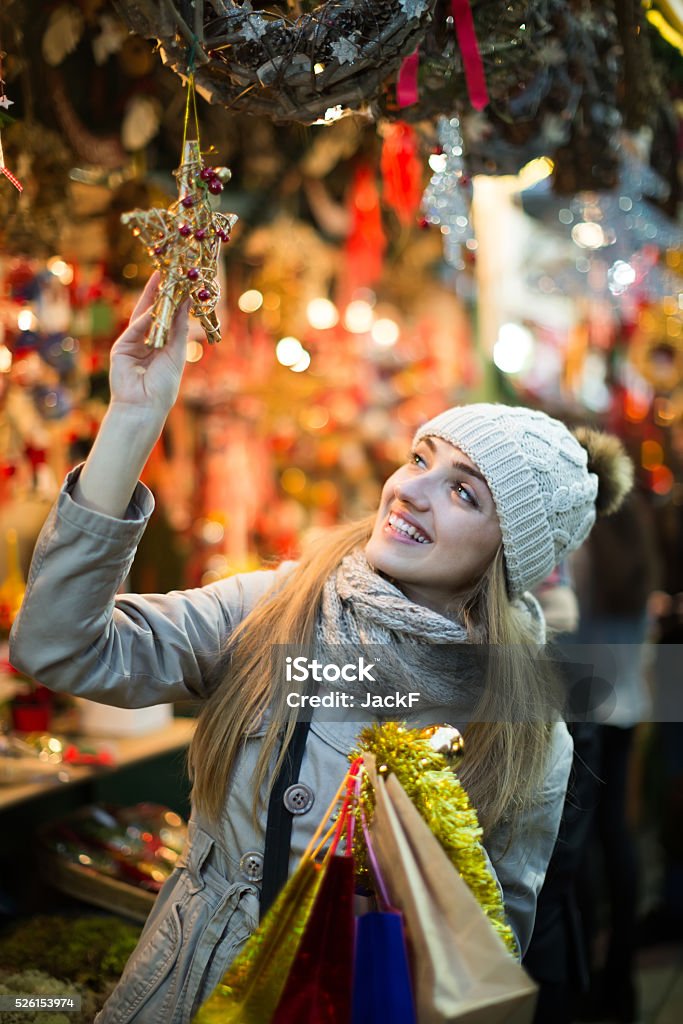 Girl choosing Christmas gifts outdoor Portrait of smiling longhaired girl near counter with Christmas gifts in evening time Adult Stock Photo