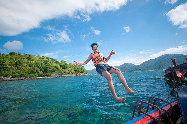 Man jumping off the boat into the ocean
