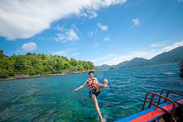 istock Man jumping off the boat into the ocean 526154074