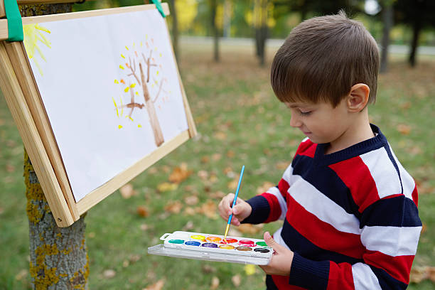 istock little happy boy drawing in park 526155058