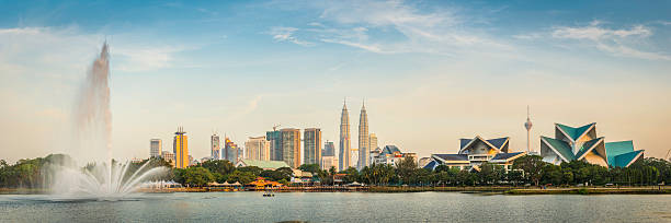 Kuala Lumpur Petronas Towers landmark cityscape skyscrapers fountain sunset Malaysia Warm sunset light illuminating the Petronas Towers and downtown skyscrapers of Kuala Lumpur, Malaysia's vibrant capital city, as they soar over the leafy foliage and fountains Taman Tasik Titiwangsa lake. ProPhoto RGB profile for maximum color fidelity and gamut. twin towers malaysia stock pictures, royalty-free photos & images