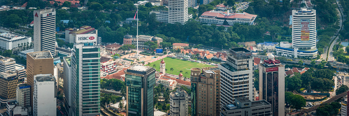 Aerial view through the skyscrapers of downtown Kuala Lumpur to the green lawn of Merdeka Square, the landmark Sultan Abdul Samad Building and Malaysia's National Flag, the historic heart of Malaysian independence. ProPhoto RGB profile for maximum color fidelity and gamut.