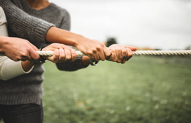 ziehe dabei das seil für teamwork - contest togetherness human hand unity stock-fotos und bilder