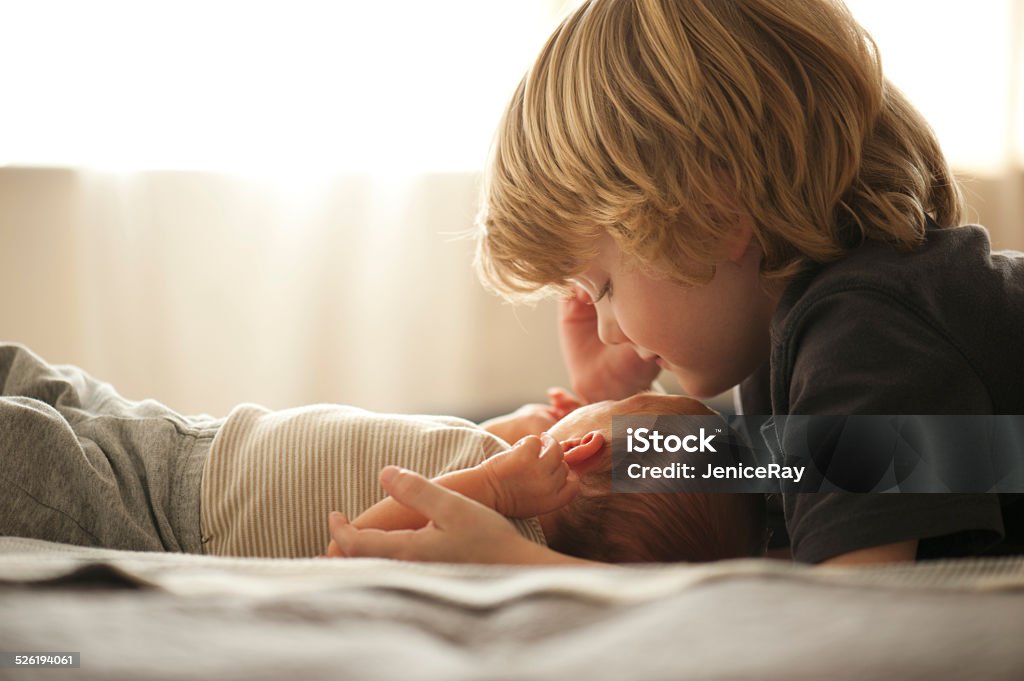 Big brother Big brother smiling at newborn brother sister Baby - Human Age Stock Photo