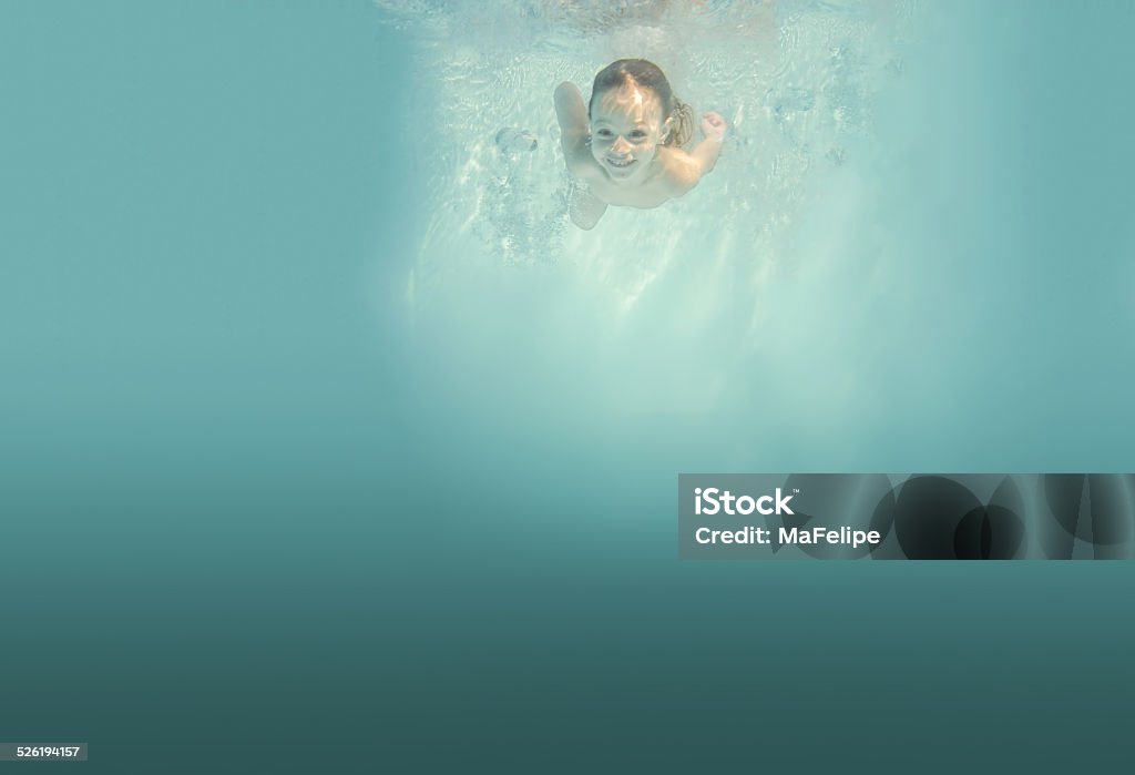 Smiling 3-year-old Child Diving Underwater A underwater photography taken in Niteroi, Rio de Janeiro, Brazil. A little 3 year old caucasian girl has just jumped into the water and is swimming looking to the camera and smiling. She is surrounded by bubbles and the water is clear and light blue. Niteroi Stock Photo