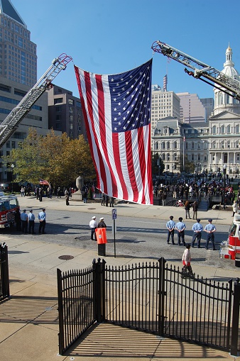 Baltimore, Maryland USA - November 11, 2014: US flag is hoisted as current soldiers and police stand for Veteran's Day Celebration. 